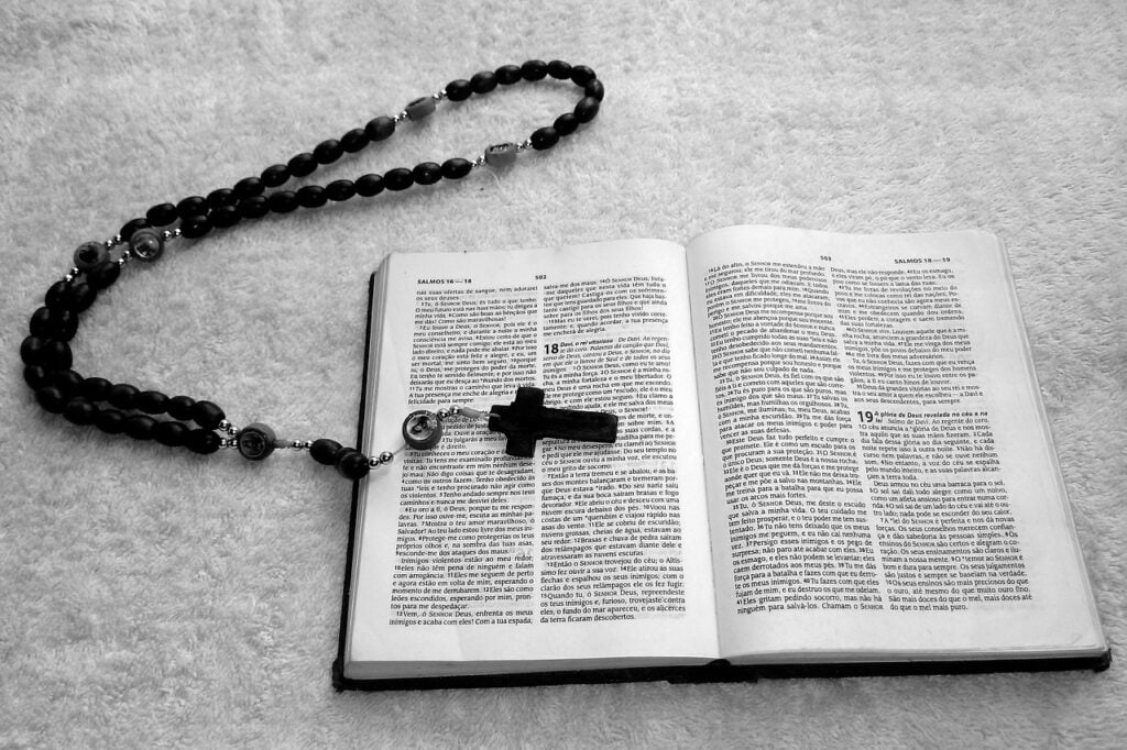 Gescheiterter Exorzismus: Religiöser Spinner tötet Familie. Das Foto ist in schwarz-weiß es zeigt eine aufgeschlagene Bibel, auf der ein Kreuz liegt.