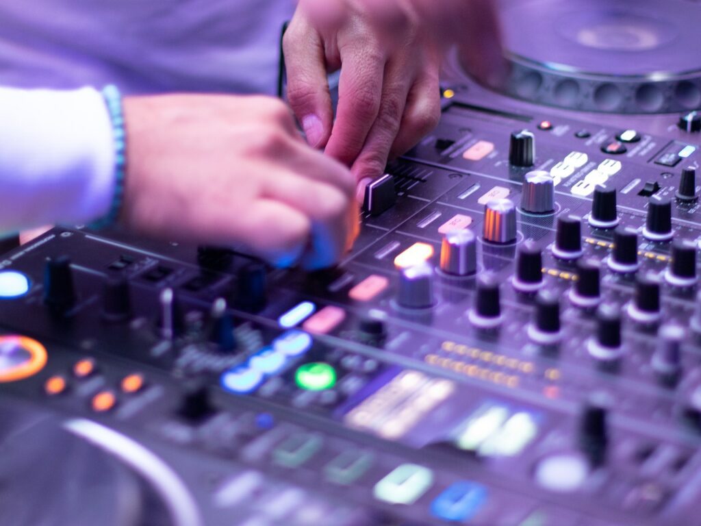 Song von Gigi D’Agostino für rechte Parolen missbraucht. Auf dem Foto sieht man Hände, die auf DJ-Equipment spielen.