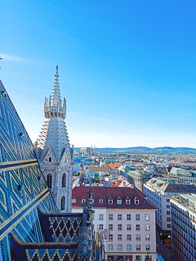 Auf dem Foto sieht man eine Luftaufnahme von der Stadt Wien. Auf der linken Bildseite ist ein Teil Daches vom Stephansdom zu sehen. Und die rechte Bildhälfte fühlt die Wiener Innenstadt aus. Das Bild steht symbolisch für die Wien Hymne.