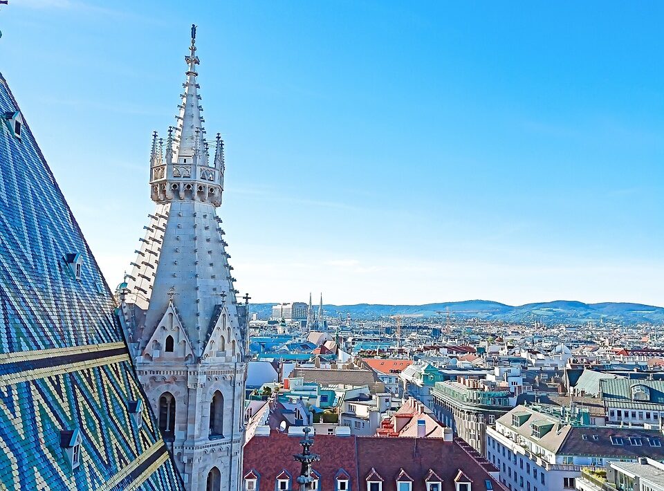 Auf dem Foto sieht man eine Luftaufnahme von der Stadt Wien. Auf der linken Bildseite ist ein Teil Daches vom Stephansdom zu sehen. Und die rechte Bildhälfte fühlt die Wiener Innenstadt aus. Das Bild steht symbolisch für die Wien Hymne.