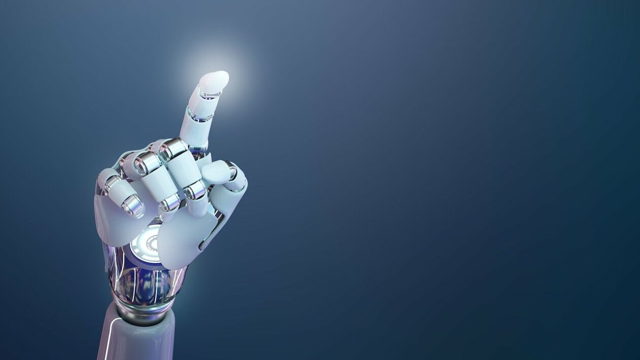 Das Bild zeigt eine futuristische, hochentwickelte Armprothese, die sich deutlich an menschlicher Anatomie orientiert. Die künstliche Hand ist in einem eleganten Weiß gehalten, kombiniert mit silbernen, metallischen Gelenken und Verbindungsstücken, die ein hohes Maß an Beweglichkeit und technischer Raffinesse suggerieren. Die Prothese ist so positioniert, dass der Zeigefinger nach oben zeigt – als würde sie auf etwas hinweisen oder kurz davor sein, etwas zu aktivieren. An der Spitze des Fingers ist ein leichtes Leuchten zu erkennen, was auf eine Interaktion mit digitaler Technologie oder eine symbolische Darstellung von Innovation und Fortschritt hinweisen könnte. Im Hintergrund ist ein glatter Farbverlauf von dunklem Blau zu einem helleren Ton zu sehen, der den Fokus klar auf die Prothese lenkt und eine moderne, beinahe sterile Atmosphäre schafft. Die Bildkomposition vermittelt eine Mischung aus technologischem Optimismus und Präzision. Die Darstellung der Armprothese wirkt nicht nur funktional, sondern fast ästhetisch – sie steht sinnbildlich für den Fortschritt in der Medizintechnik, insbesondere in der Prothetik und Robotik.