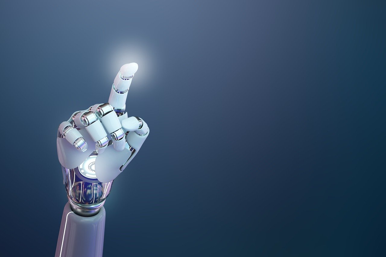 Das Bild zeigt eine futuristische, hochentwickelte Armprothese, die sich deutlich an menschlicher Anatomie orientiert. Die künstliche Hand ist in einem eleganten Weiß gehalten, kombiniert mit silbernen, metallischen Gelenken und Verbindungsstücken, die ein hohes Maß an Beweglichkeit und technischer Raffinesse suggerieren. Die Prothese ist so positioniert, dass der Zeigefinger nach oben zeigt – als würde sie auf etwas hinweisen oder kurz davor sein, etwas zu aktivieren. An der Spitze des Fingers ist ein leichtes Leuchten zu erkennen, was auf eine Interaktion mit digitaler Technologie oder eine symbolische Darstellung von Innovation und Fortschritt hinweisen könnte. Im Hintergrund ist ein glatter Farbverlauf von dunklem Blau zu einem helleren Ton zu sehen, der den Fokus klar auf die Prothese lenkt und eine moderne, beinahe sterile Atmosphäre schafft. Die Bildkomposition vermittelt eine Mischung aus technologischem Optimismus und Präzision. Die Darstellung der Armprothese wirkt nicht nur funktional, sondern fast ästhetisch – sie steht sinnbildlich für den Fortschritt in der Medizintechnik, insbesondere in der Prothetik und Robotik.